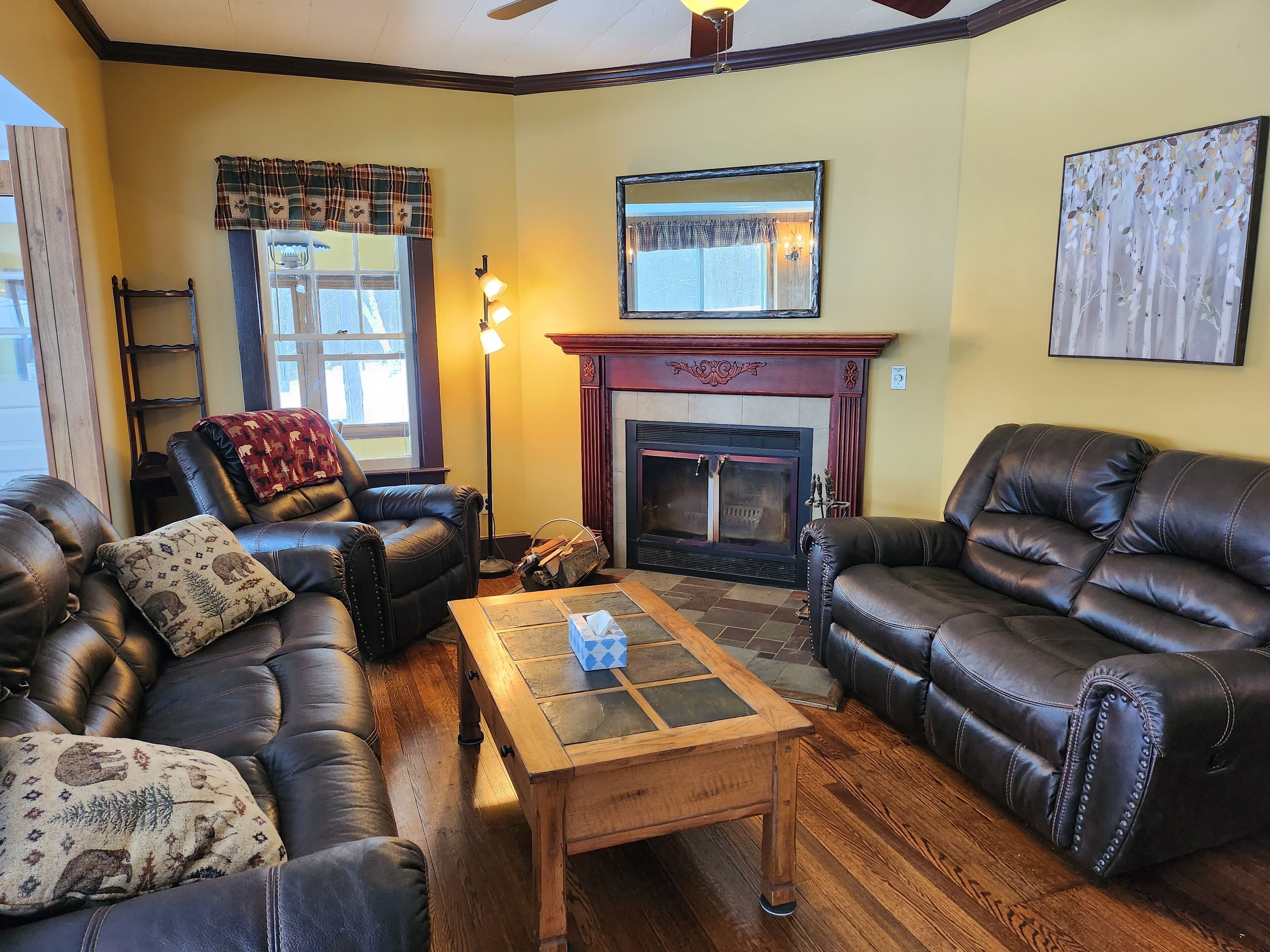 A living room with two leather sofas, a wooden coffee table, a fireplace, and a large mirror on the wall.