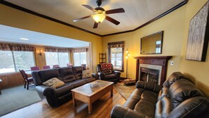 A living room with leather sofas, a wooden coffee table, and a fireplace. - Lake George 5 Bed/ 3 Bath home w/ lake & resort access (Lake George)