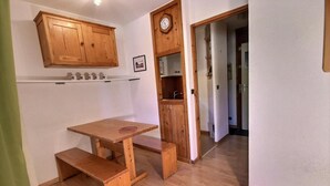 Une cuisine compacte avec des meubles de rangement en bois, un évier encastré et une petite table.