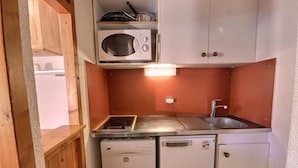 Une petite cuisine équipée d’un four à micro-ondes, d’une cuisinière, d’un évier et d’un lave-vaisselle.