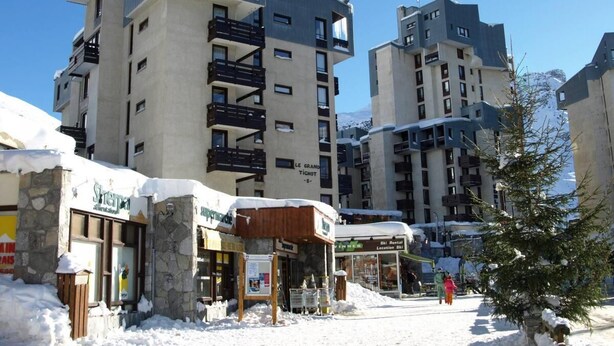 Un bâtiment enneigé, doté de nombreux balcons et d’une enseigne indiquant un service de location de matériel de ski.