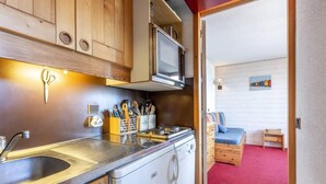 A compact kitchen with wooden cabinets, a stainless steel sink, and a stove.