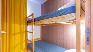 A bunk bed room with a ladder, a curtain, and a wooden door.