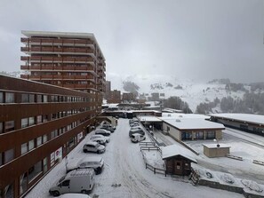 Eine mehrgeschossige Parkgarage mit mehreren Autos, umgeben von Gebäuden und einer verschneiten Landschaft.