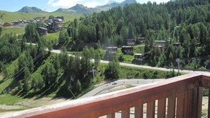 Un pueblo montañoso con casas tradicionales rodeado de bosques frondosos y un cielo despejado.