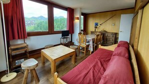 Una habitación acogedora con cama, una mesa de madera, un escritorio y una silla. Hay una ventana con vistas a montañas y una lámpara.