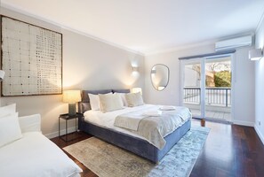 Una camera da letto moderna con un letto grande, un comodino, uno specchio fissato alla parete e vista sull'esterno tramite una porta scorrevole.