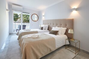 A hotel room with two beds, a balcony, a round mirror, and a modern lamp. - Oxford Park II with pool by Portugal Portfolio (Cascais)