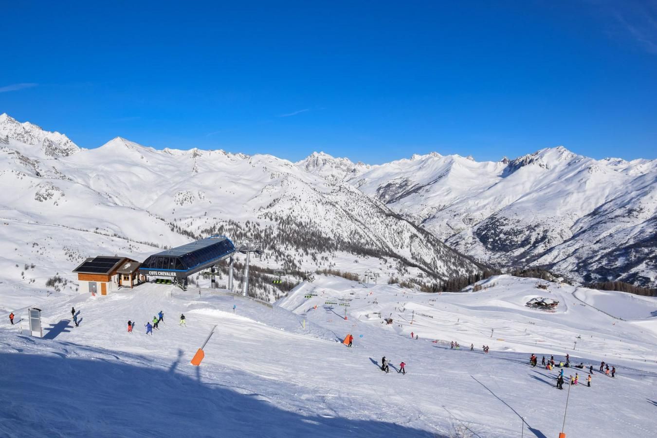 Une station de ski dotée d’un chalet, de pistes de ski et de montagnes enneigées.