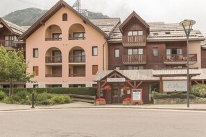 Un hôtel doté de nombreux balcons, d’un petit espace extérieur aménagé avec des sièges et d’une enseigne indiquant la présence d’un restaurant.