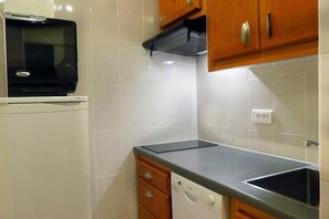 Kitchen area with refrigerator, microwave, and dishwasher, featuring cabinets and a countertop.