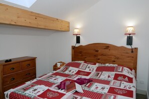 Cozy retreat with a quilted bedspread, wall-mounted reading lights, and a nightstand.