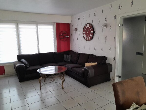 A living room with a sectional sofa, a coffee table, and a wall clock. - city break  (Coudekerque-Branche)