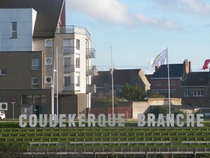 A building with a sign reading "COUDEKERQUE BRANCH" and a flagpole with flags. - city break  (Coudekerque-Branche)