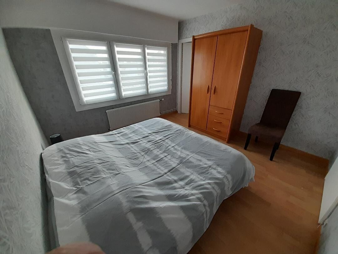 A bedroom with a bed, a wardrobe, a radiator, and a window with blinds.