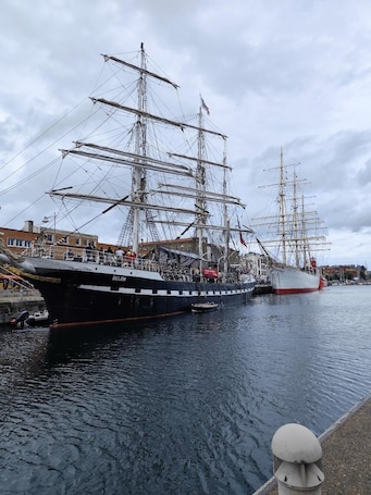 A large sailing ship docked at a harbor with a cityscape in the background.. city break