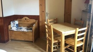 A small room with a wooden bed, a wooden table with chairs, and a door.