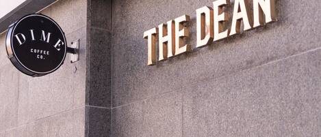 A building facade with a sign reading "THE DEAN" and a coffee shop sign above it.