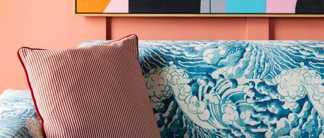A blue patterned sofa with a striped pillow against a peach wall.