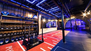 Un gimnasio con equipo de levantamiento de pesas, alfombra roja y techo con iluminación azul.