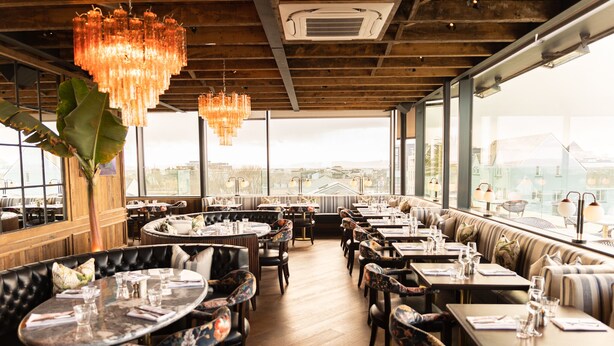 Un restaurante con mesas redondas, cabinas y vistas a la ciudad.