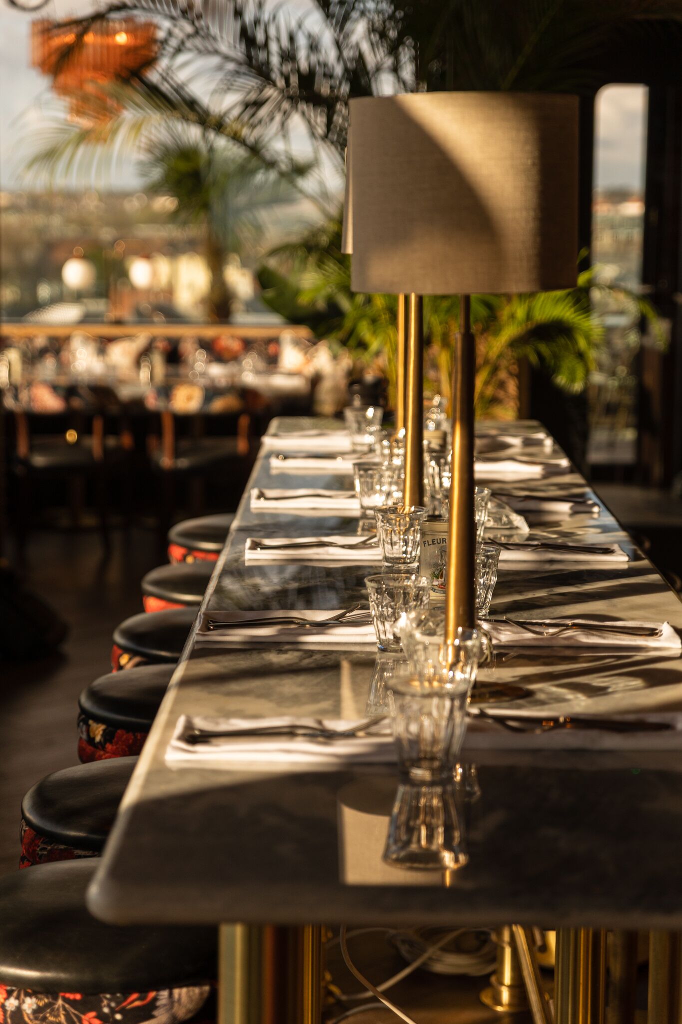 A restaurant table set with glassware, plates, and cutlery, with a lamp and a menu stand.