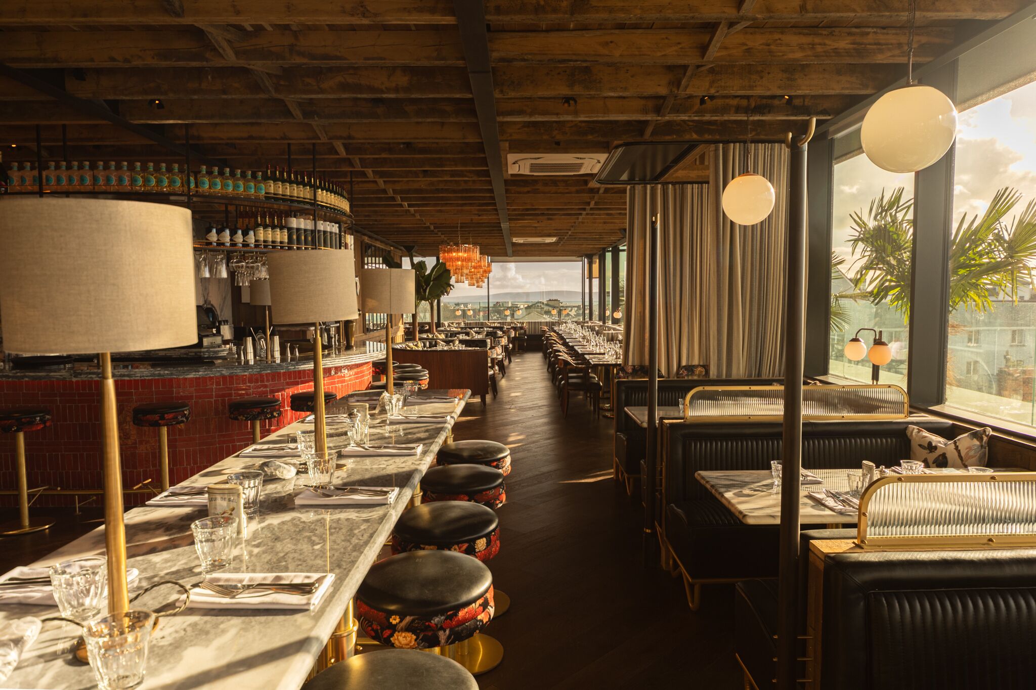 A restaurant with long communal tables, bar area, and high ceilings.