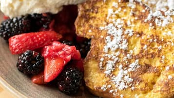 A plate with pancakes, whipped cream, and fresh berries.