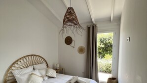 Un dormitorio con una cama grande, una lámpara colgante y vistas a zonas verdes.