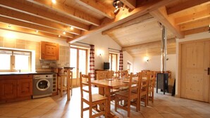 A spacious kitchen with wooden cabinets, a washing machine, and a dining area with wooden tables and chairs. - 100m from ski slopes, 1st floor, balcony, fireplace or stove, tv, ski locker, 90m², Val Cenis (Lanslebourg-Mont-Cenis)