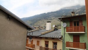 A traditional European village with buildings featuring balconies and satellite dishes, set against a backdrop of mountains and a cloudy sky. - 100m from ski slopes, 1st floor, balcony, fireplace or stove, tv, ski locker, 90m², Val Cenis (Lanslebourg-Mont-Cenis)