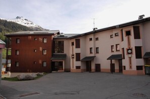 Edifício com um pátio central, apresentando uma combinação de fachadas de madeira e bege, com montanhas ao fundo.