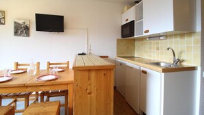 A compact kitchen with a wooden table and chairs, a built-in microwave, and a sink.