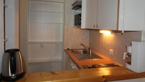 A compact kitchen with white cabinets, a stainless steel sink, and a coffee maker.