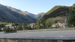 A mountain town with a paved road, stone walls, and buildings with traditional architecture.