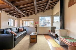 A cozy living room with a black leather sofa, a wooden coffee table, and a fireplace. - Rome As You Feel - Cozy Apt. in Navona (Rome)