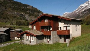 A multi-story chalet with stone and wood exterior, balconies, and a mountainous backdrop. - 300m from ski slopes, balcony, tv, ski locker, 20m², Val Cenis (Lanslevillard)