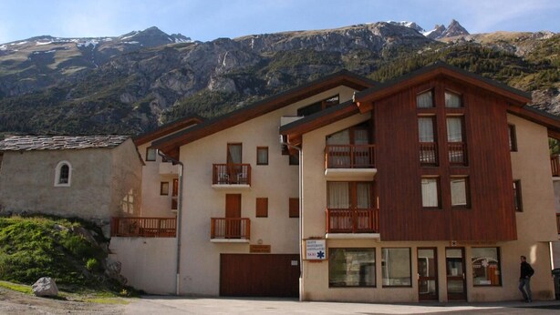 Ein zweistöckiges Gebäude mit Holzfassade, Balkonen und einem Schild, das ein Finanzamt anzeigt.