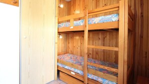 Ein Zimmer mit einem Holzbett mit Etagen und einer gemusterten Matratze.