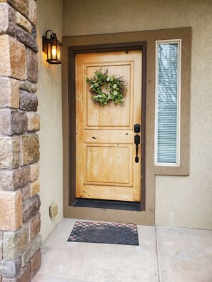 A wooden front door with a wreath, a mailbox, and a welcome mat.