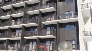 A multi-story hotel with a modern architectural design, featuring balconies on each floor and a stone facade. - 2nd floor, balcony, tv, ski locker, 25m², Flaine (Flaine)