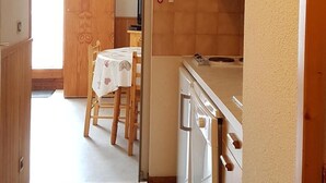Kapea keittiö, jossa on astianpesukone, mikroaaltouuni sekä ruokailutila, jossa on pöytä ja tuolit.