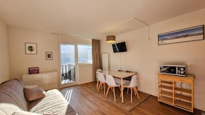 A modern living room with a sofa, a dining table with chairs, a flat-screen TV, a microwave, and a balcony with a view. - 300m from ski slopes, 2nd floor, view ski slopes, balcony, tv, ski locker, 25m², Flaine (Flaine)