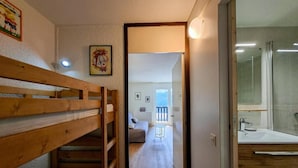 A narrow hallway with a bunk bed on the left, a small round table in the center, and a bathroom with a glass shower on the right. - 300m from ski slopes, 2nd floor, view ski slopes, balcony, tv, ski locker, 25m², Flaine (Flaine)