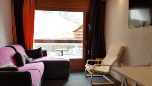Una habitación con cama, una silla, una mesa y ventana con vistas a un edificio.