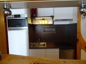 A compact kitchen with a built-in oven, a sink, and a dishwasher.