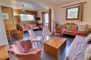 A cozy room with a wooden floor, a sofa, a coffee table, and a TV.