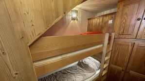 A bunk bed with wooden headboard and footboard, a small shelf, and a wall-mounted light fixture. - 20m from shops, 4th floor, view street, balcony, tv, ski locker, 25m², Les Menuires (Les Menuires)