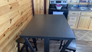 Une cuisine avec des murs en bois, une table noire et un poêle.