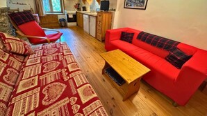 A cozy living room with a red sofa, a patterned red and gold rug, and a wooden coffee table.